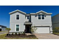 Charming two-story home with light-gray siding, manicured landscaping, and a two-car garage at 16248 Saint Kitts Cir, Clermont, FL 34714