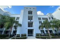 Modern condo exterior featuring multiple stories and private balconies, complemented by lush tropical landscaping at 4741 Clock Tower Dr # 201, Kissimmee, FL 34746