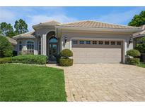 Charming home featuring a lush green lawn, a brick driveway, manicured shrubbery, and a neutral tan color scheme at 512 Weston Pl, Debary, FL 32713