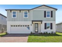 Two-story home with a combination of vertical and horizontal siding, a brick driveway, and an attached garage at 312 Castle Dr, Lake Alfred, FL 33850