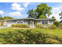 Charming gray brick home featuring a bright yellow front door and manicured front lawn at 520 Oriole Dr, Lakeland, FL 33803