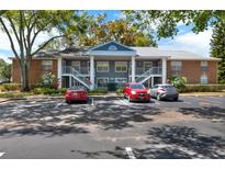 Condo building with brick accents, white railings, and ample parking at 5429 Lake Margaret Dr # E, Orlando, FL 32812