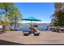 Lounge chairs and outdoor umbrella on deck with lake and dock views at 7841 Georgeann St, Winter Park, FL 32792