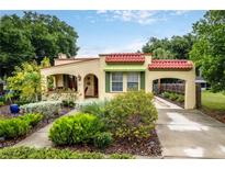 Charming home featuring a red tile roof, arched entry, and a lush, landscaped front yard at 809 Poinsettia Dr, Eustis, FL 32726