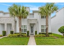 Modern two-story home featuring a well-manicured lawn, stone accents, and decorative palm trees on a sunny day at 17522 Hidden Forest Dr, Clermont, FL 34714