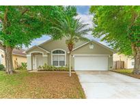 Charming single-story home featuring a well-manicured lawn, mature trees, and a two-car garage at 2104 Remington Pointe Blvd, Kissimmee, FL 34743