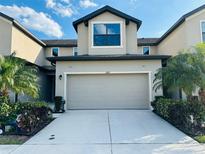 Charming townhome with a two-car garage, beautiful landscaping, and a well-lit driveway on a sunny day at 2285 Seven Oaks Dr, St Cloud, FL 34772