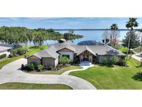 Stunning lakefront home with lush landscaping, circular driveway, and beautiful waterfront views at 29150 Beauclaire Dr, Tavares, FL 32778