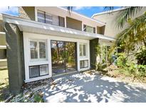 A covered back patio features sliding glass doors, outdoor lighting, and well maintained landscaping at 6114 Peregrine Ave # D03, Orlando, FL 32819