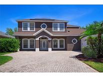 Two-story home boasts well-manicured landscaping, brick driveway, and a welcoming front entrance with white trim at 7299 Vista Park Blvd, Orlando, FL 32829