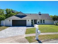 Charming single-story home with a well-manicured lawn and a paved driveway under a clear, sunny sky at 9012 Notchwood Ct, Orlando, FL 32825