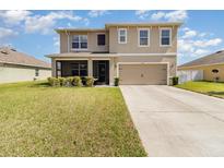 Two-story home featuring a two-car garage, well-maintained lawn, and inviting screened-in porch, enhancing its curb appeal at 9731 Pepper Tree Trl, Wildwood, FL 34785