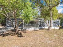 Charming gray home featuring a covered front porch framed by mature trees and a well-maintained yard at 1041 Osceola Trl, Casselberry, FL 32707