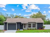 Charming home with a well-manicured lawn, gray color scheme, and a paved driveway leading to an attached garage at 1811 Oakgrove Ave, Deltona, FL 32725