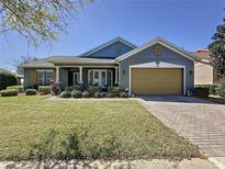 Charming single-story home with a well-manicured lawn and a brick-paved driveway leading to an attached two-car garage at 228 Bayou Bend Rd, Groveland, FL 34736