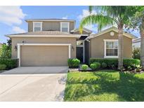 Charming two-story home with a well-manicured lawn, a two-car garage, and a welcoming front entrance at 2319 Grantham Ave, Davenport, FL 33837