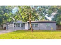 Charming single-story home with a gray exterior, well-manicured lawn, and mature trees offering ample shade at 2421 Laura Pl, Orlando, FL 32803