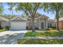 Charming single-story home with a well-maintained lawn and two-car garage, nestled under a mature shade tree at 2867 Oconnell Dr, Kissimmee, FL 34741