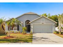 Charming single-story home featuring a manicured lawn, palm trees, and an attached two-car garage at 4231 Mendenwood Ln, Orlando, FL 32826