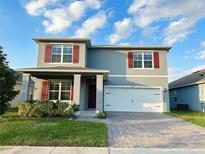 Charming two-story home with a gray exterior, red shutters, a brick driveway, and a two-car garage at 5384 Palomino Pl, Apopka, FL 32712