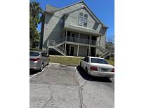 Two story building with light green exterior, gray metal staircases, and assigned parking out front on a sunny day at 6142 Westgate Dr # 304, Orlando, FL 32835