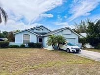 Attractive home with a blue exterior, mature palm trees, and a well-maintained front yard at 72 Saint Kitts Cir, Winter Haven, FL 33884