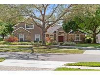 Charming home with a well-manicured lawn and stone accents beneath a large, shady tree at 9548 Crown Prince Ln, Windermere, FL 34786