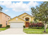 Charming two-story home featuring a well-manicured lawn, colorful shrubbery, and an attached two-car garage at 2787 Lido Key Dr, Kissimmee, FL 34747