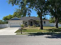 Charming home with a well-manicured front yard, mature trees, and a two car garage on a sunny day at 402 S Hudson St, Orlando, FL 32835