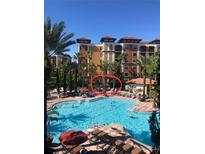 Beautiful resort pool area with lush landscaping, palm trees, and lounge chairs under clear blue skies at 12544 Floridays Resort Dr # 103B, Orlando, FL 32821
