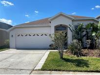 Charming one-story home with a two-car garage, well-maintained lawn and verdant tropical landscaping at 1352 Royal Saint George Dr, Orlando, FL 32828