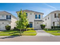 Charming two-story home featuring a well-manicured lawn and a bright blue front door and shutters at 1551 Flange Dr, Davenport, FL 33896