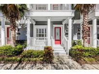 Charming townhome entrance with vibrant red door, complemented by lush landscaping and elegant white columns at 165 Rosette Dr, Winter Springs, FL 32708