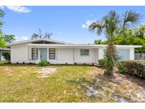 Charming single-story home featuring white siding, a light blue door, a palm tree, and a well-maintained lawn at 2319 Ashland Blvd, Orlando, FL 32808