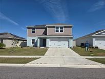 Two-story home featuring a two-car garage, neutral siding, concrete driveway and solar panels on the roof at 268 Fiddlewood Ct, Davenport, FL 33837