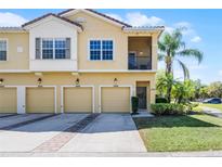 Inviting townhouse showcases a two-story elevation, four garage doors, and lush landscaping at 2898 Oakwater Dr # 2898, Kissimmee, FL 34747