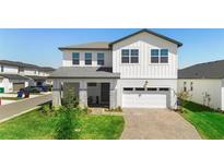 Two-story home featuring a brick driveway, an attached garage, and a well-manicured lawn at 4911 Shady Pines Dr, St Cloud, FL 34772