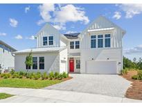 Stunning two-story white farmhouse with a paver driveway, red front door, and lush landscaping at 6244 Trailblaze Bnd, St Cloud, FL 34771
