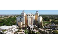 Stunning exterior view of a luxury hotel featuring towers, palm trees, and resort-style amenities at 7593 Gathering Dr # 203, Reunion, FL 34747