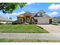 Charming two-story brick home with a manicured lawn and beautiful landscaping creating a welcoming curb appeal at 437 Wilmington Cir, Oviedo, FL 32765