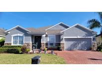 Charming single-story home with a brick driveway, stone accents, and a well-manicured front lawn at 1530 Lexington Av Ave, Davenport, FL 33837