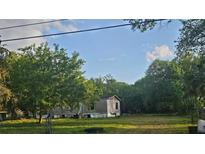 Exterior view of a home surrounded by lush greenery and an expansive lawn at 18168 Cedarhurst Rd, Orlando, FL 32820