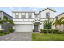 Charming two-story home features a gray brick driveway, a two-car garage, and lush landscaping at 2320 Lelani Cir, Davenport, FL 33897