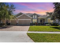 Beautiful home featuring a three-car garage, manicured lawn, brick driveway, and stunning curb appeal at 2731 Cypress Tree Trl, St Cloud, FL 34772