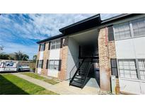 Brick and painted siding two-story apartment building with covered walkway and metal stairs to upper units at 5317 Curry Ford Rd # O201, Orlando, FL 32812