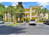 Charming yellow condominium complex with white railings, surrounded by lush landscaping and convenient parking at 806 Lucaya Loop, Davenport, FL 33897