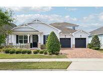 Charming, single-Gathering home featuring a three-car garage, manicured lawn, and stone accents at 8366 Randal Park Blvd, Orlando, FL 32832