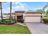 Charming single-story home featuring a stone facade, manicured lawn, and a spacious two-car garage at 9054 Sandwood Way, Orlando, FL 32832