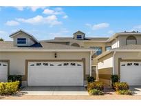 Attractive townhouse featuring a two-car garage, manicured landscaping, and a secure gated entrance at 13326 Fountainbleau Dr, Clermont, FL 34711
