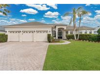 Charming single-story home boasting a three-car garage, manicured lawn, and tropical landscaping at 2877 Ashton Ter, Oviedo, FL 32765